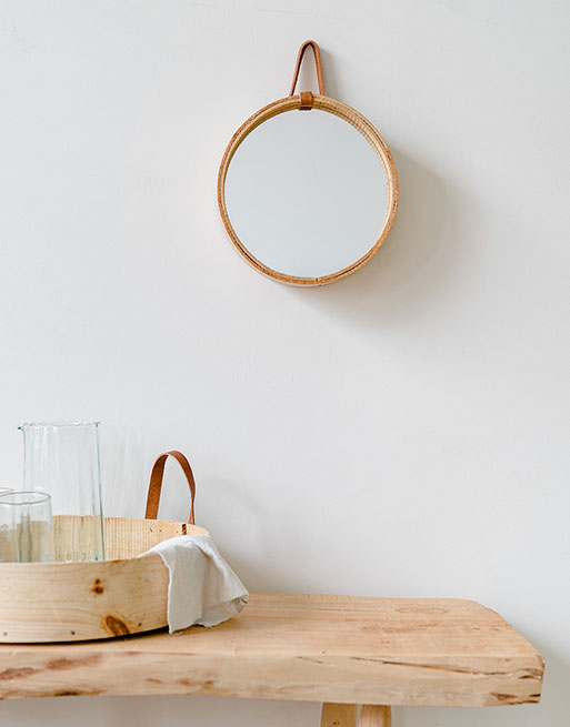 Miroir rond en bois accroché au mur au dessus d'une table en bois avec plateau