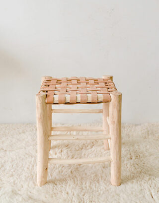 Tabouret en cuir posé sur un tapis blanc