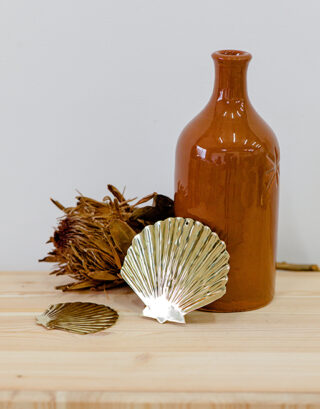 Coquillages en laiton posés contre un vase terracotta