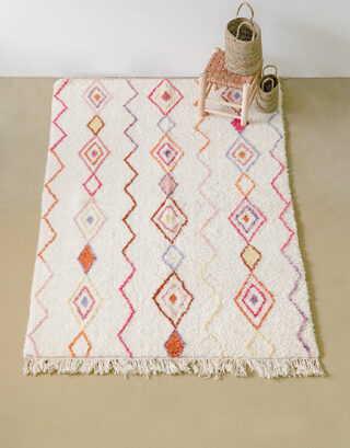 Grand tapis pastel vu du haut avec petit tabouret en cuir et panier tressé