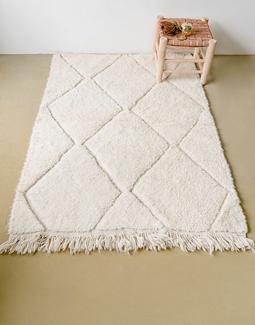 Notre tapis à losanges blancs en relief vue du haut avec un tabouret en cuir dessus