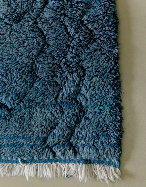 Franges blanches sur ce tapis en laine coloré bleu