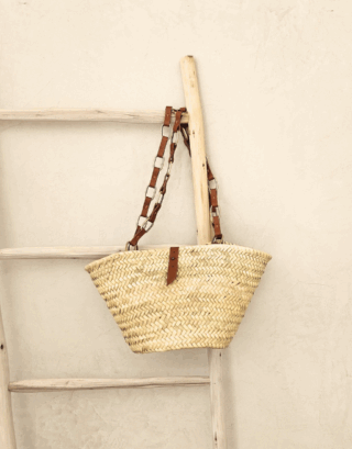 Notre panier Cherine avec ses chaînes en laiton et cuir, accroché à une échelle en bois