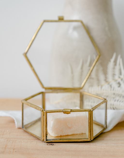 Boîte à bijoux en verre dorée ouverte près de fleurs séchées