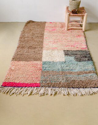 Tapis aux couleurs douces vu du haut avec petit tabouret en cuir et panier tressé