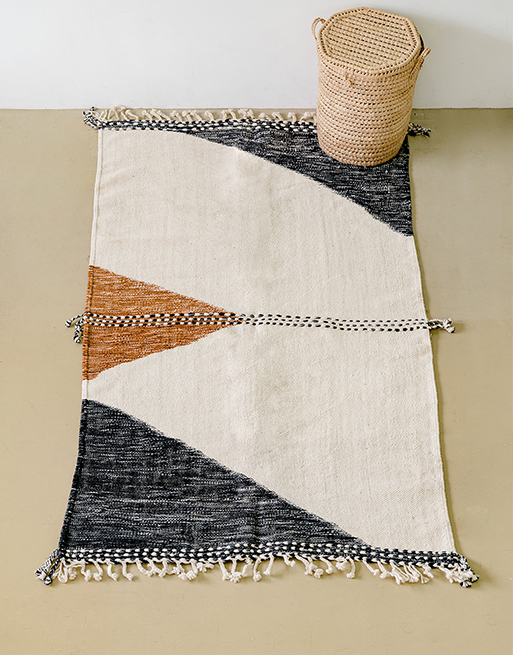 Tapis laine tressée à motifs vu du haut avec panière à linge ronde en feuilles de palmier