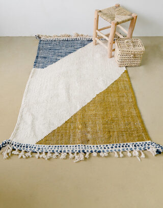Tapis artisanal marocain vu de haut avec petit tabouret paille et une malle en feuilles de palmier