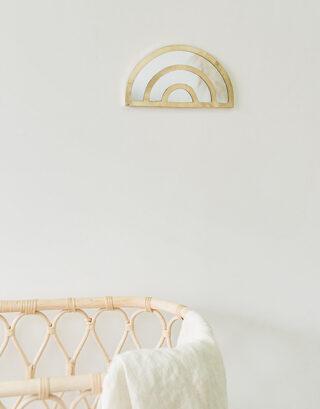 Miroir arc-en-ciel accroché au mur près d'un berceau en rotin