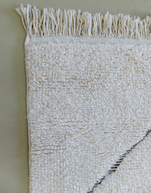 Focus sur les franges en laine de ce tapis à losanges