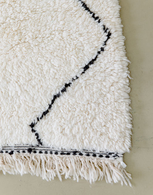 Détails des broderies et franges sur l'un des côtés du tapis en laine tressée
