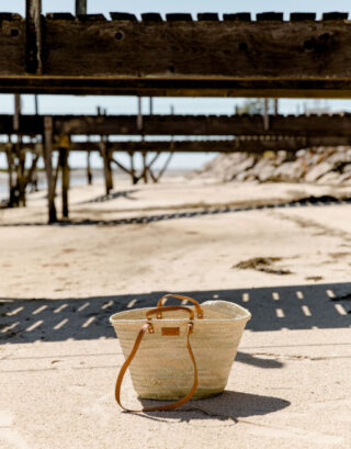 Panier en paille et anses cuir camel sur une plage