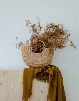 Panier décoratif posé sur un meuble avec bouquet de fougère