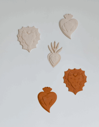 Notre ensemble d'ex-voto en argile rouge et blanche accroché au mur.