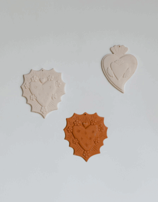 Notre ensemble d'ex-voto en argile rouge et blanche accroché au mur.