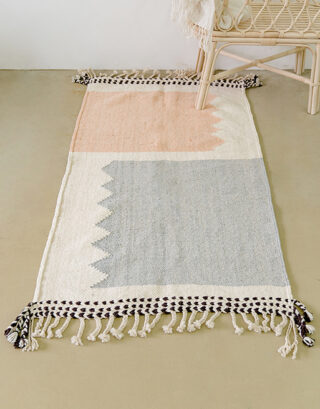 Tapis marocain pastel vu du haut avec un joli berceau en rotin