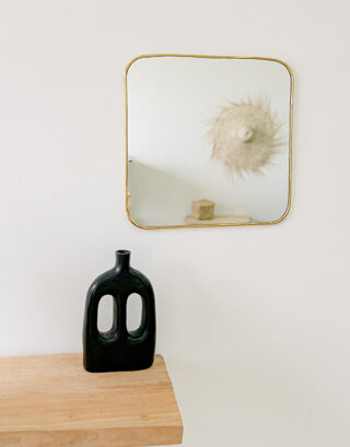 Miroir carré accroché au mur près d'un vase noir