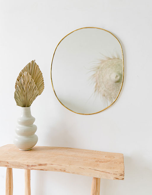 Miroir rond irrégulier accroché au mur au dessus d'une table en bois