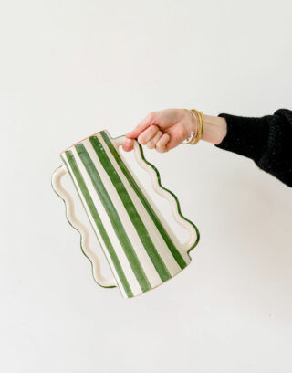 Notre vase rayé vert posé sur une table avec des fleurs séchées