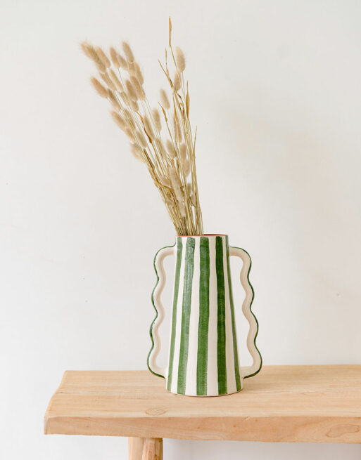 Notre vase rayé vert posé sur une table avec des fleurs séchées