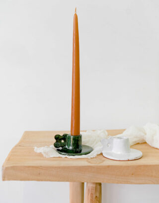 Nos deux modèles de bougeoir fleur en argile posés sur une table en bois