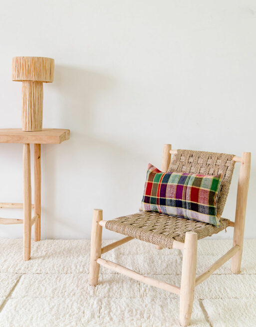 Notre coussin posé sur un fauteuil en paille dans un décor naturel