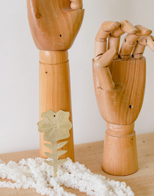 Zoom sur la fleur en laiton posée contre les mains en bois de mannequin