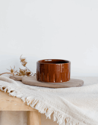 Notre bol creusé posé sur une planche en bois près d'un plaid écru et d'une fleur séchée