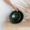 Notre saladier rond posé sur une table en bois près d'une feuille de palmier