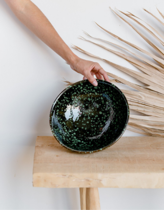 Notre saladier rond posé sur une table en bois près d'une feuille de palmier