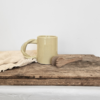 Notre tasse en argile avec sa anse torsadée posée sur une table près d'une serviette en lin écrue
