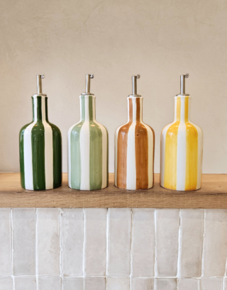 Notre huilier posé sur une table en bois, disponible dans 4 coloris : vert, matcha, jaune et marron.