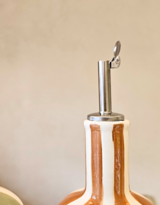 Notre huilier posé sur une table en bois, disponible dans 4 coloris : vert, matcha, jaune et marron.