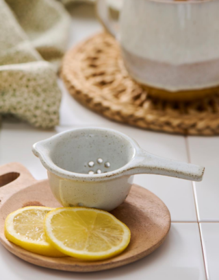 L'infuseur à thé, posé sur une table près de tranches de citron