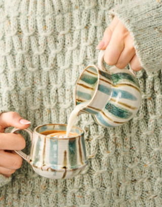 Pichet à lait près d'une tasse tenu par une femme