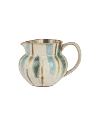 Pichet à lait près d'une tasse tenu par une femme