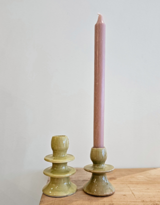 Notre bougeoir olive posé sur une table avec une bougie dedans