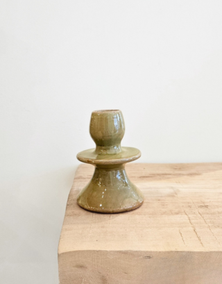 Notre bougeoir olive posé sur une table avec une bougie dedans