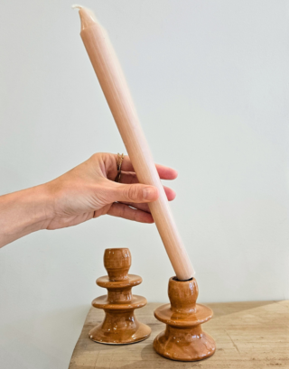 Notre bougeoir terracotta posé sur une table avec une bougie dedans