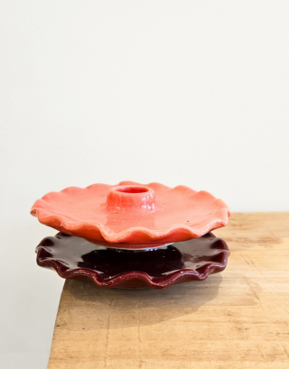 Bougeoir en argile posé sur une table en bois et un autre dans les mains