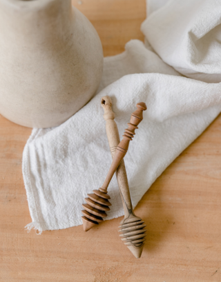 cuillère à miel posé sur une table en bois avec une serviette en lin