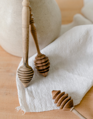 cuillère à miel posé sur une table en bois avec une serviette en lin