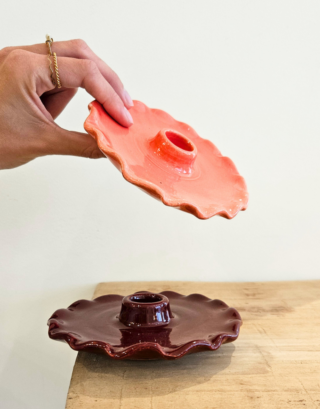 Bougeoir en argile posé sur une table en bois et un autre dans les mains