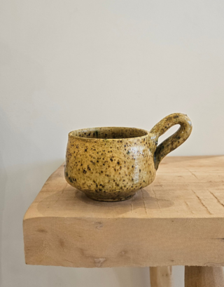 Tasse en Tamegroute posée sur une table en bois près d'un torchon vichy
