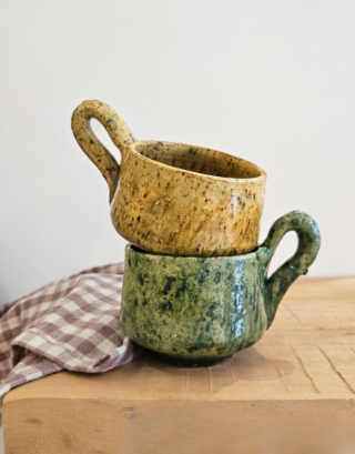 Tasse en Tamegroute posée sur une table en bois près d'un torchon vichy