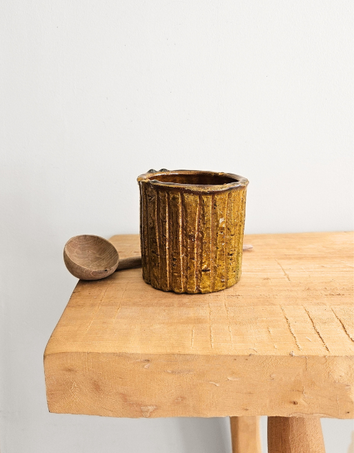 Joli pot en Tamegroute posé sur une table en bois près d'une cuillère en noyer.